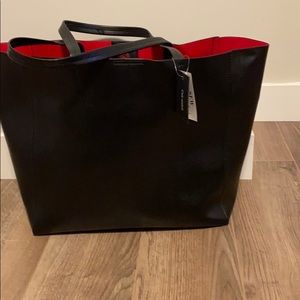 Black leather tote bag with red coated interior